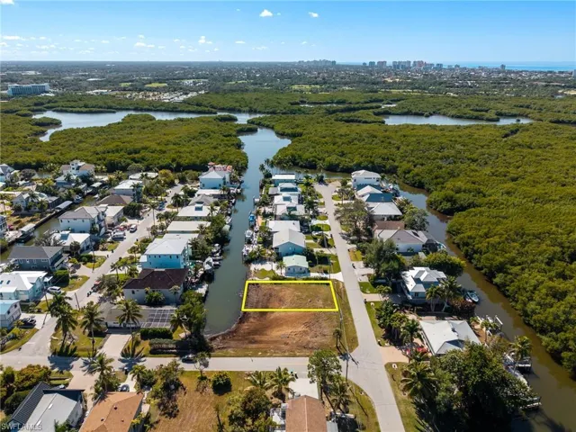 Aerial view of property and surrounding area featuring a nearby body of water, property boundaries highlighted, and nearby suburban area