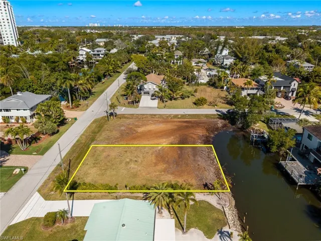 Aerial view of property and surrounding area with a nearby body of water and property parcel outlined