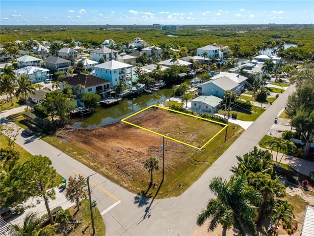 Aerial perspective of suburban area with property parcel outlined and a nearby body of water