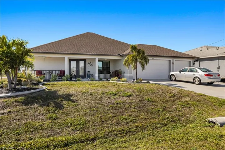 Ranch-style home with a garage, a front lawn, and a porch