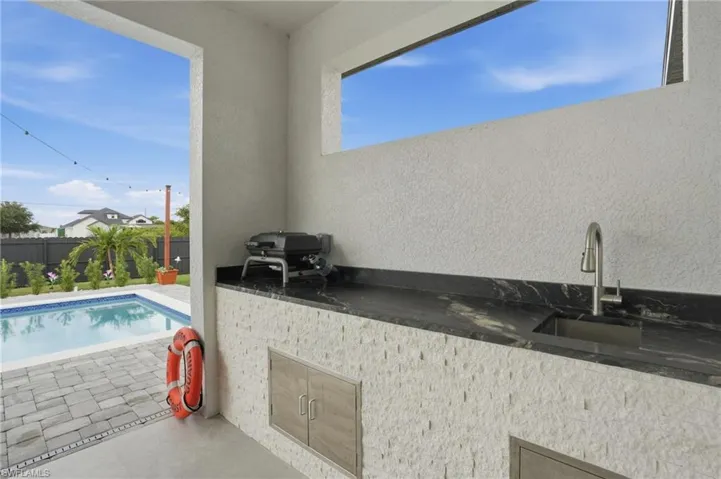 View of swimming pool with a patio area and an outdoor kitchen