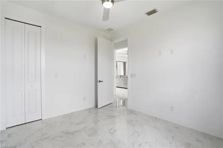 Unfurnished bedroom with light marble finish floors, ceiling fan, and a closet
