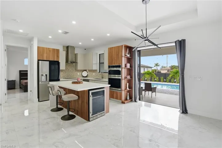 Kitchen featuring brown cabinets, open shelves, a breakfast bar area, a center island, and recessed lighting