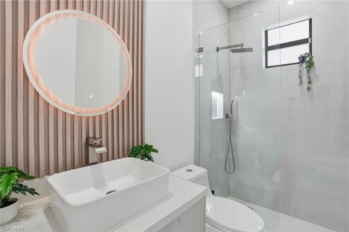 Bathroom with vanity, walk in shower, and wallpapered walls