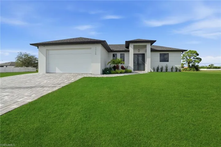 Prairie-style home featuring decorative driveway, stucco siding, an attached garage, and a shingled roof