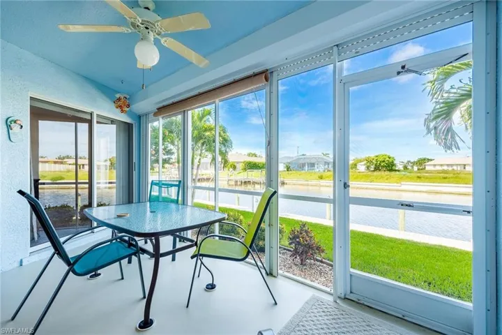 Sunroom with ceiling fan and a water view