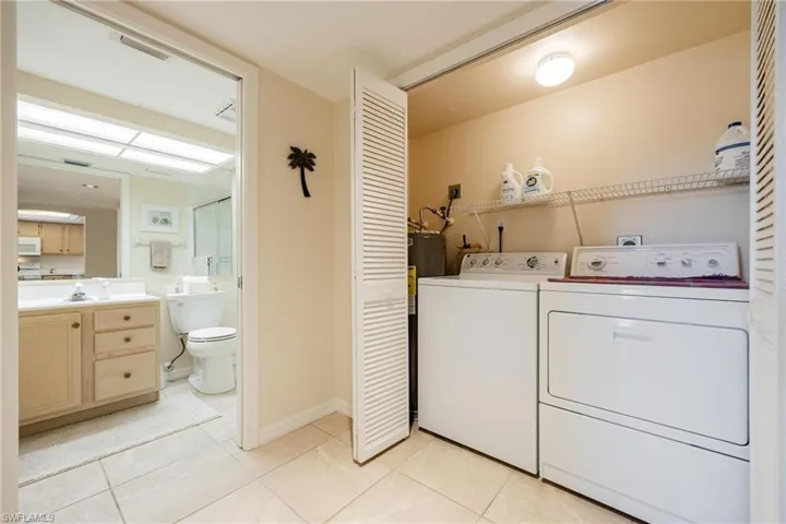 Washroom with light tile patterned floors and independent washer and dryer
