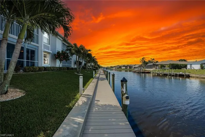 View of dock with a water view and a lawn