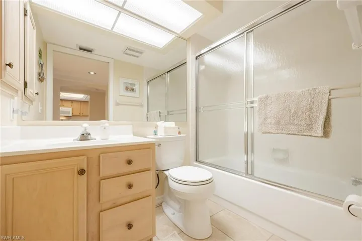 Full bathroom with shower / bath combination with glass door, vanity, toilet, and tile patterned flooring