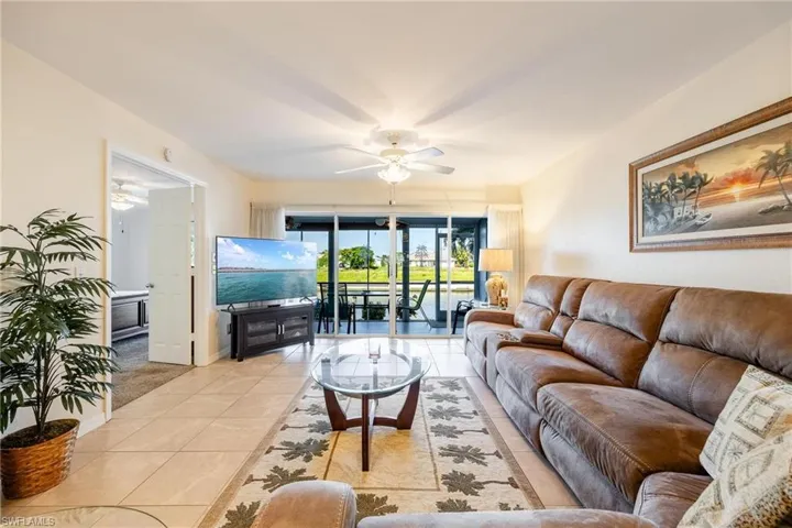 Living room with ceiling fan and light tile patterned flooring