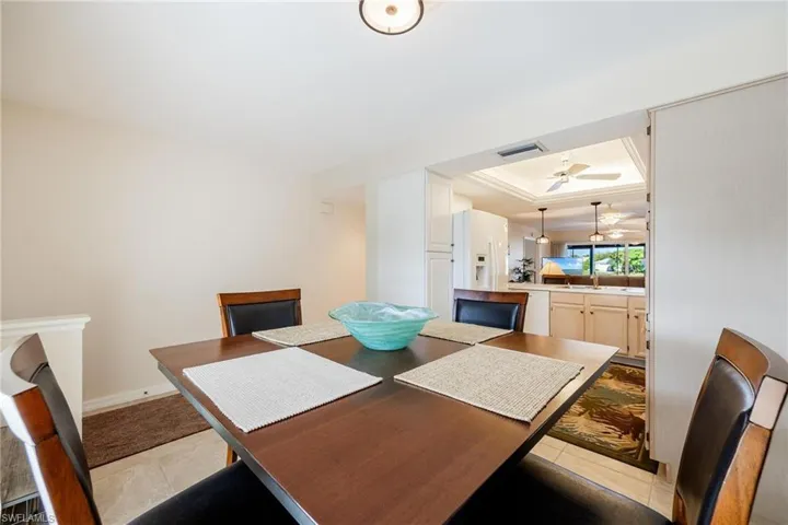 Tiled dining room with a tray ceiling, sink, and ceiling fan