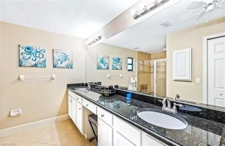 Bathroom featuring tile patterned floors, vanity, ceiling fan, and an enclosed shower