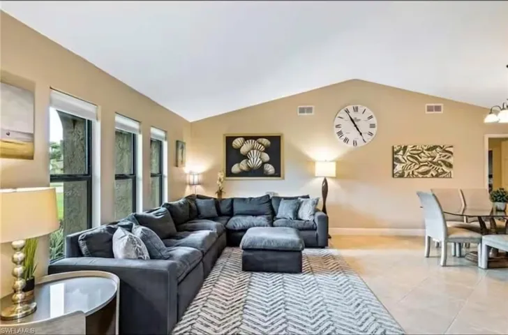 Living room with light tile patterned floors, vaulted ceiling, and a notable chandelier