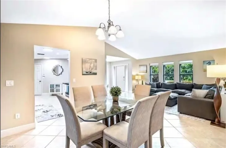 Dining area featuring light tile patterned flooring, high vaulted ceiling, and a chandelier