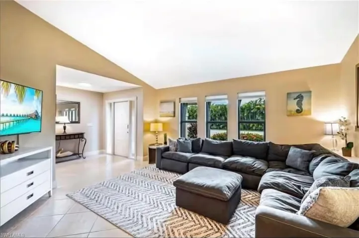 Living room featuring light tile patterned flooring and high vaulted ceiling