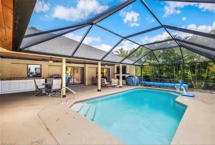View of swimming pool with a patio, glass enclosure, and ceiling fan