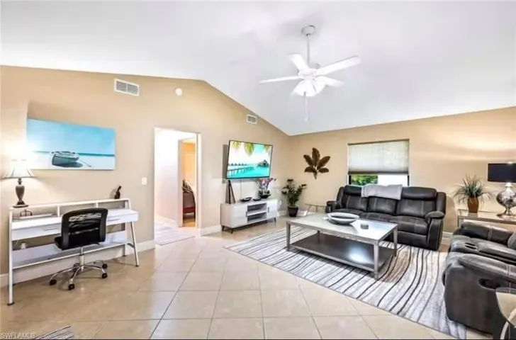 Living room featuring light tile patterned floors, vaulted ceiling, and ceiling fan