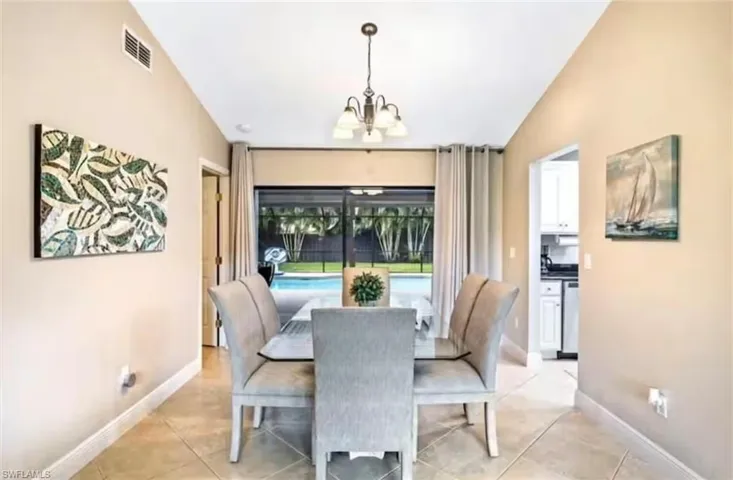 Tiled dining room featuring a notable chandelier and lofted ceiling