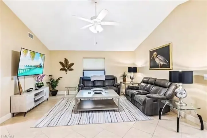 Tiled living room featuring ceiling fan and lofted ceiling