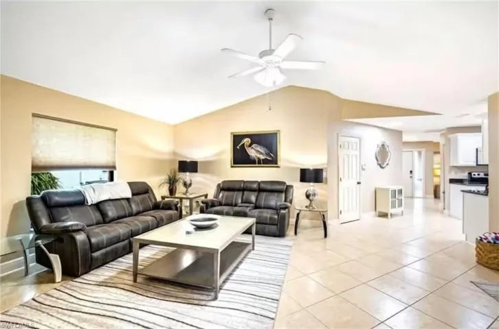 Tiled living room featuring ceiling fan and vaulted ceiling