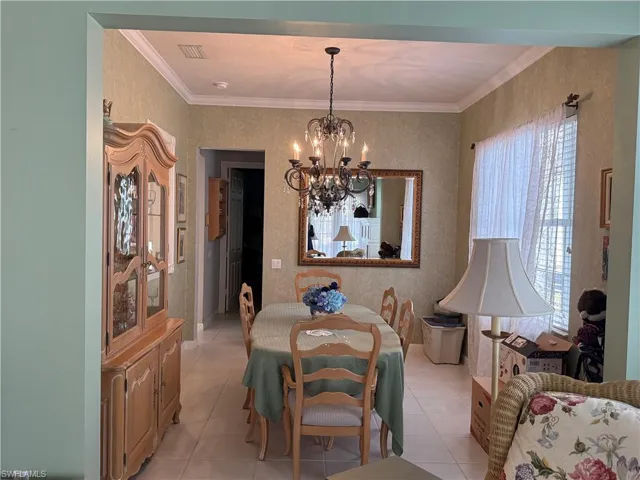 Formal dining room with elegant chandelier, crown molding, and spacious layout for entertaining.