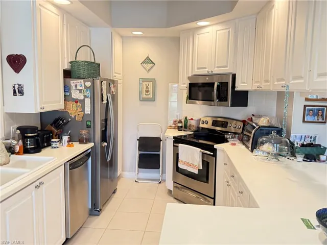 Bright kitchen with white cabinetry, stainless steel appliances, ample counter space, and recessed lighting.