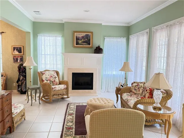 Elegant living area with fireplace, soaring ceilings, abundant natural light, and charming garden views.