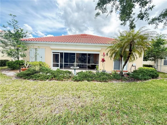 Private rear exterior with screened lanai, lush tropical landscaping, and spacious backyard setting.