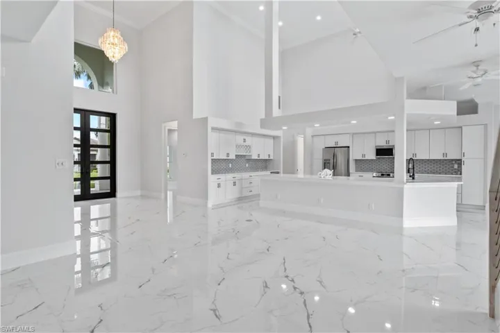 This dramatic entryway features 10-foot modern French doors and brand-new hurricane impact windows, inviting you into a home that exudes elegance.