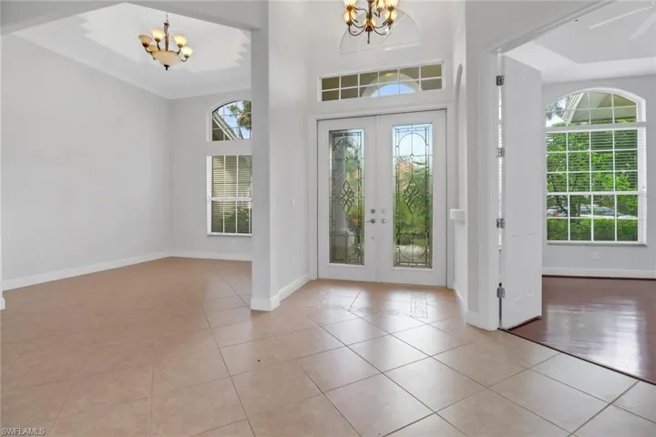 Entrance foyer with a notable chandelier, french doors, plenty of natural light, and light tile floors