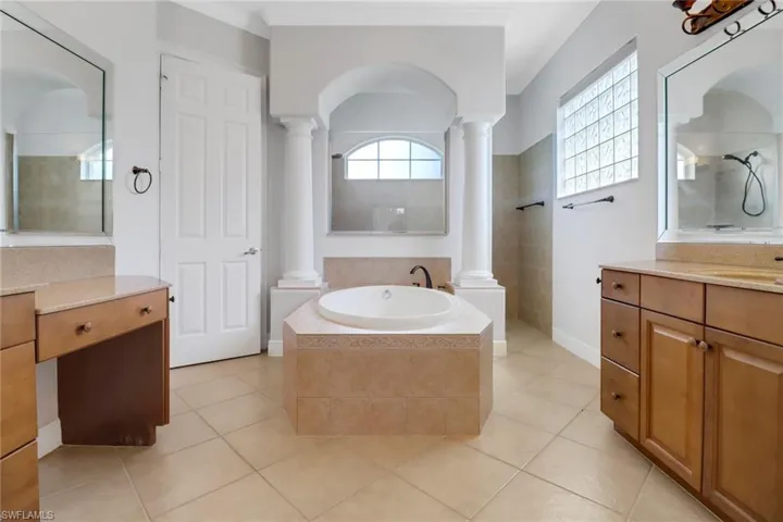 Main bathroom with ornate columns, walk-in shower, a relaxing soaking tub, vanity & tile flooring