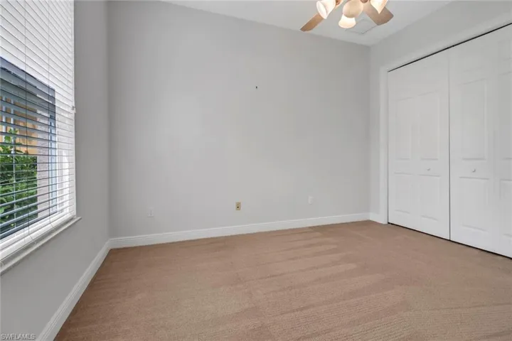 Guest bedroom featuring ceiling fan, light colored carpet & large wall closet