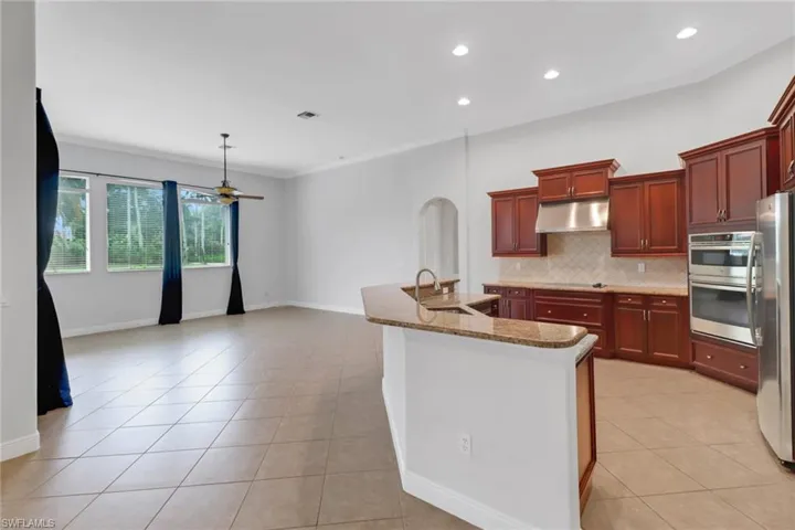Kitchen with decorative backsplash, light tile patterned flooring, appliances with stainless steel finishes, and sink