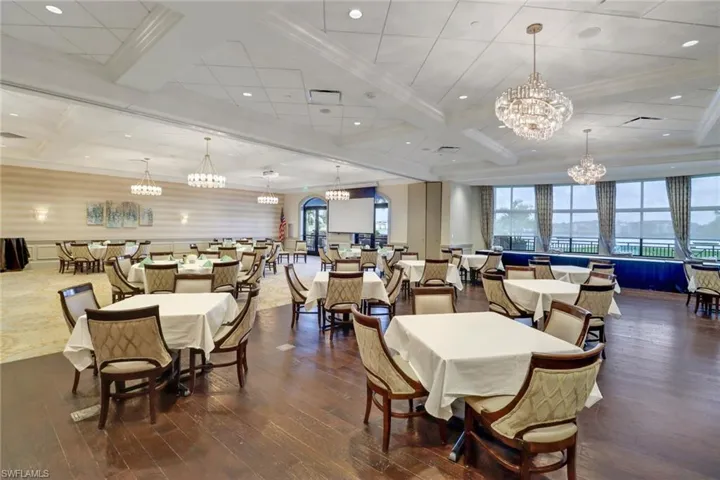 Light & bright Clubhouse dining room featuring dark wood-type flooring & beautiful chandeliers