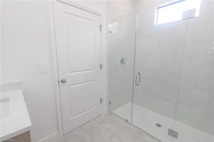 Full Jack and Jill bathroom featuring tile  floors, vanity, and a marble finish shower