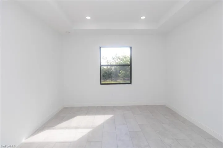 Master bedroom with a raised ceiling, visible vents, baseboards, and tile floors.