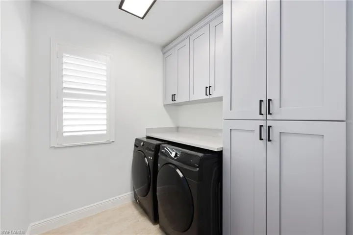 Laundry area featuring washing machine and dryer and cabinets