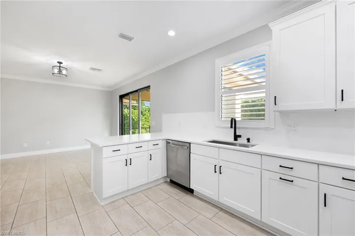 Kitchen featuring a wealth of natural light, sink, dishwasher, and kitchen peninsula