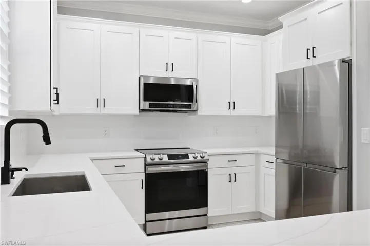 Kitchen with appliances with stainless steel finishes, sink, and white cabinets