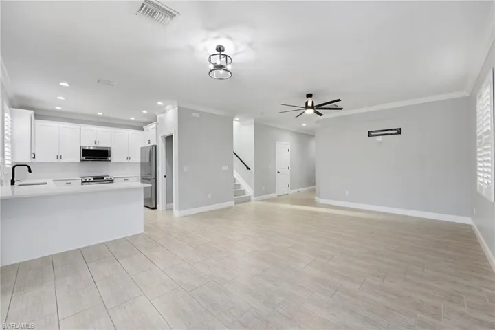 Unfurnished living room featuring ornamental molding, sink, and ceiling fan