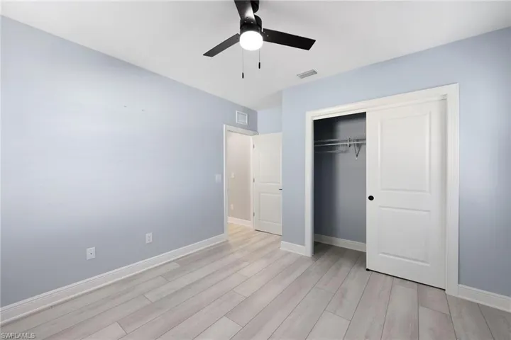 Unfurnished bedroom featuring a closet, light hardwood / wood-style floors, and ceiling fan