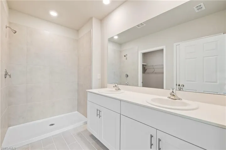 Bathroom with tile patterned flooring, a tile shower, and vanity