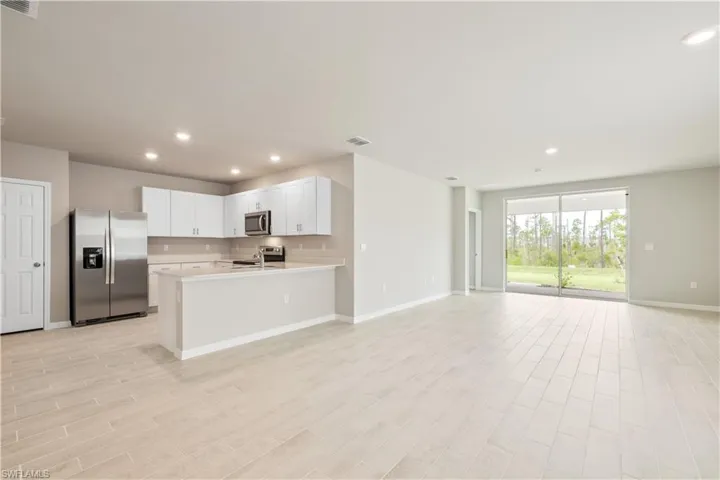 Kitchen with kitchen peninsula, white cabinetry, light hardwood / wood-style flooring, and appliances with stainless steel finishes