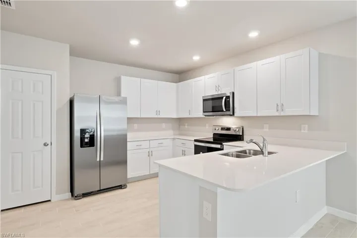 Kitchen featuring stainless steel appliances, white cabinetry, sink, light wood-type flooring, and kitchen peninsula
