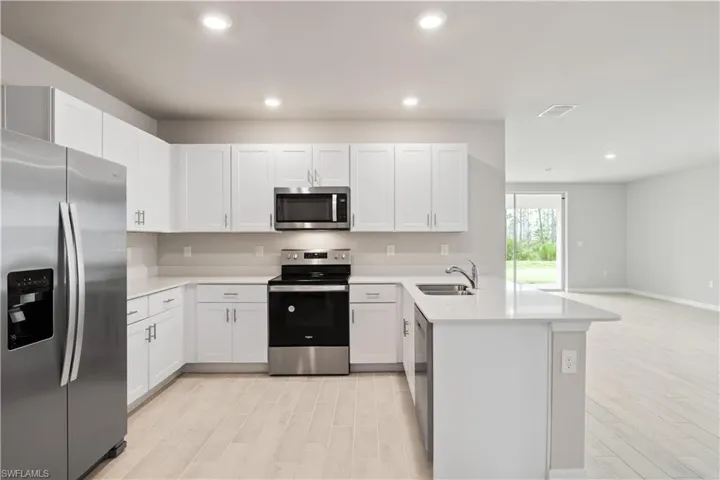 Kitchen featuring sink, appliances with stainless steel finishes, light hardwood / wood-style floors, kitchen peninsula, and white cabinets