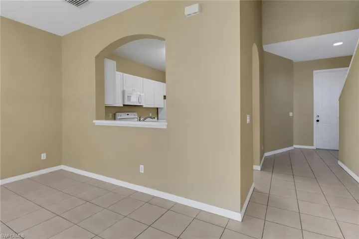 Spare room featuring light tile patterned floors and arched walkways