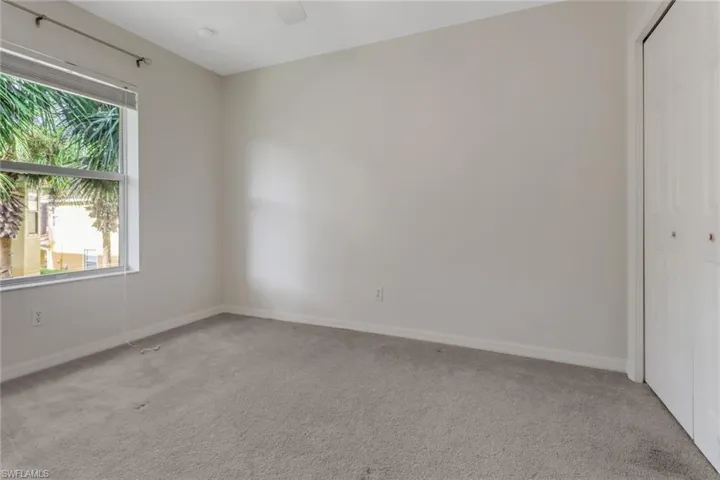 Unfurnished bedroom featuring light colored carpet, a closet, and a ceiling fan