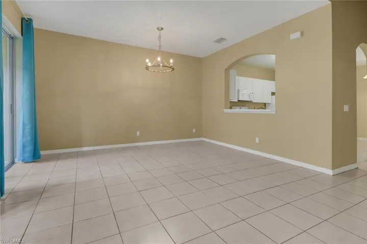 Unfurnished room with a chandelier, light tile patterned floors, and arched walkways