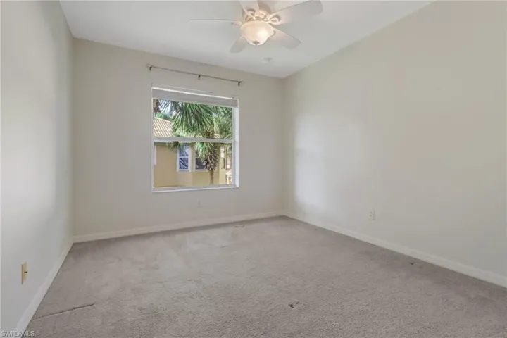 Carpeted spare room featuring baseboards and a ceiling fan