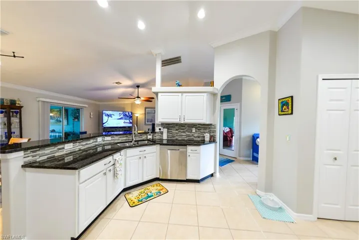 Kitchen with kitchen peninsula, dishwasher, tasteful backsplash, white cabinets, and sink